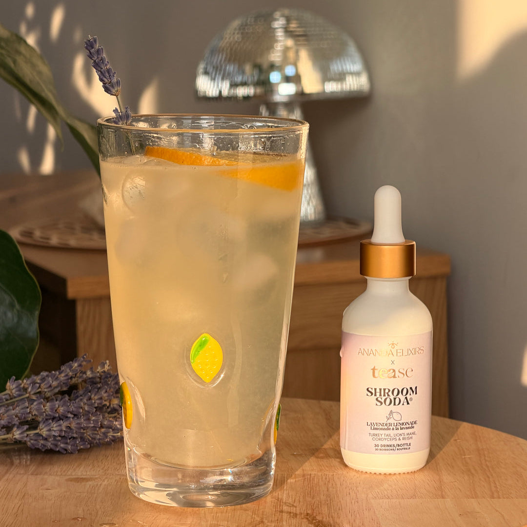 Glass of lemonade with a garnish on a wooden table next to a bottle of serum.