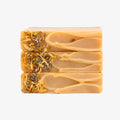 Three stacked soap bars with natural ingredients on a white background