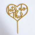 Heart-shaped cake topper with 'Let's do this' text on a white background