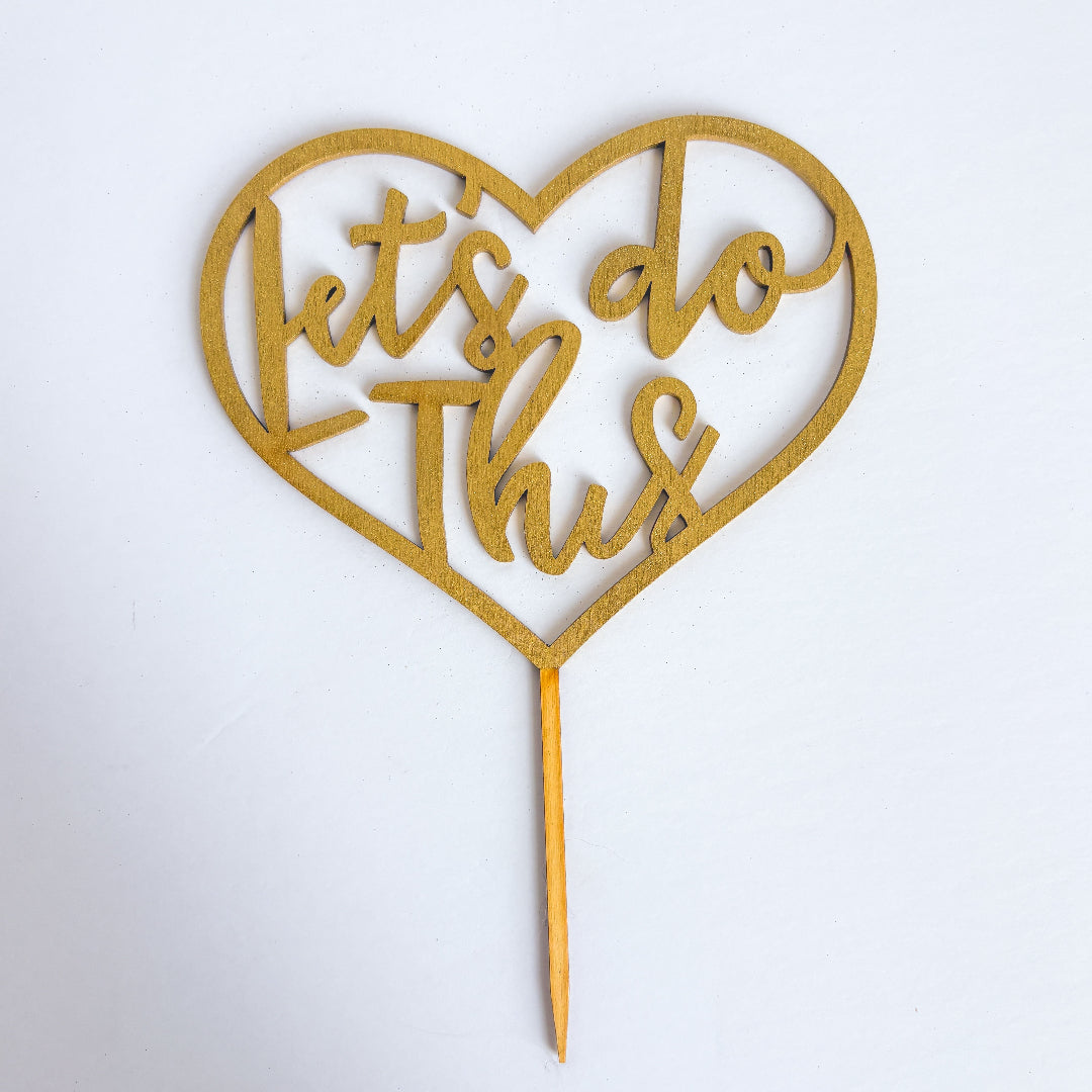Heart-shaped cake topper with 'Let's do this' text on a white background