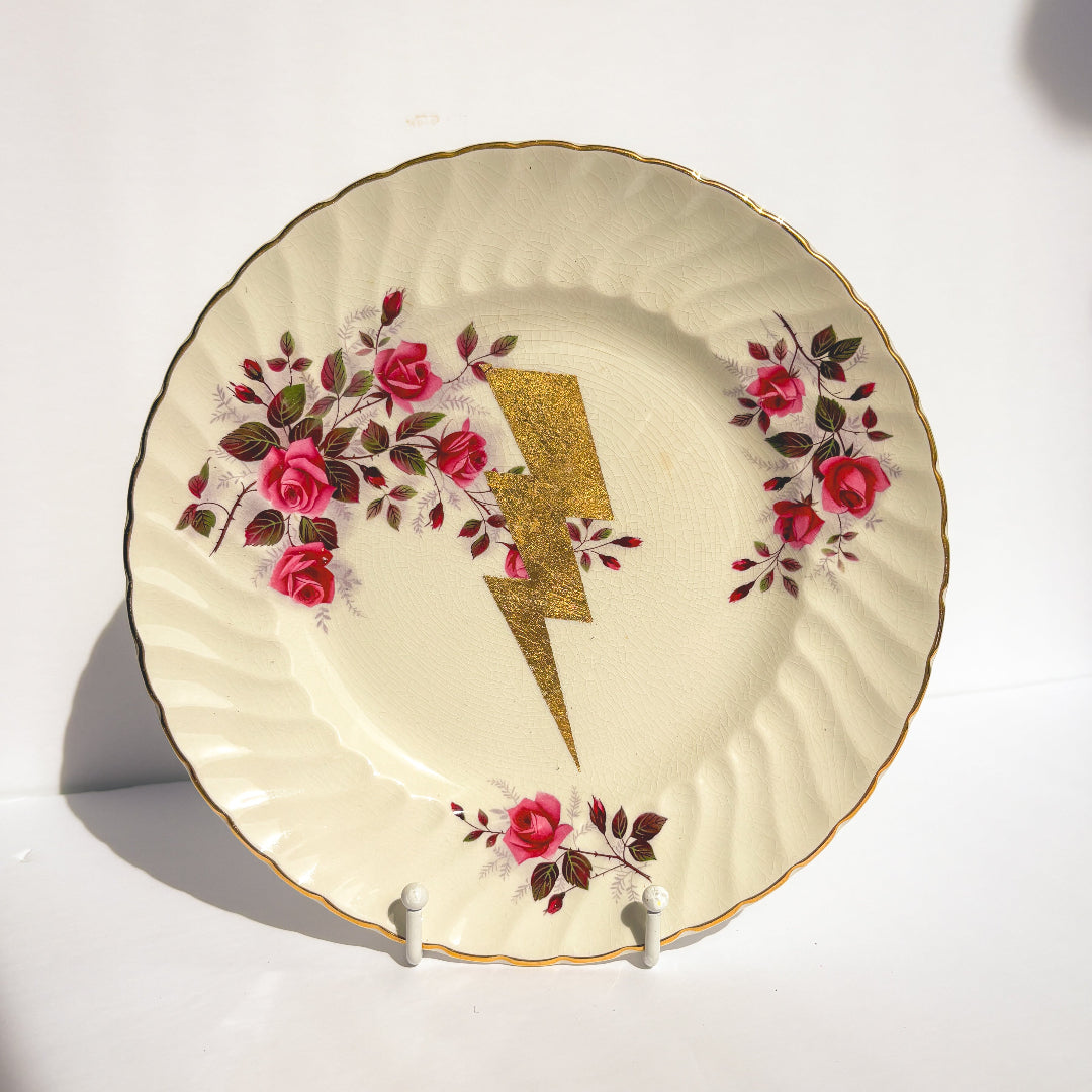 Decorative plate with floral design and gold lightning bolt on a white background
