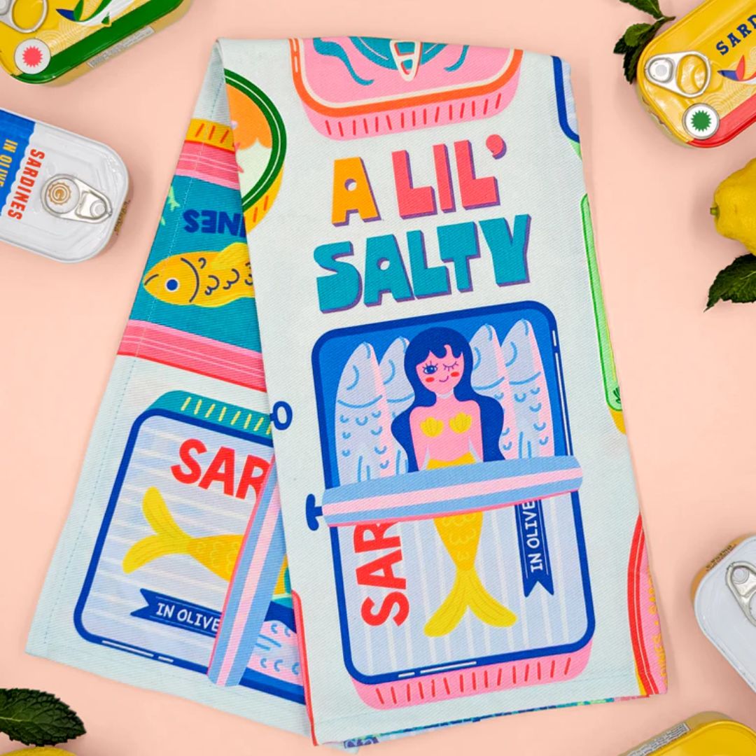 Colorful product packaging with 'A Lil Salty' text and illustrations on a light pink background.