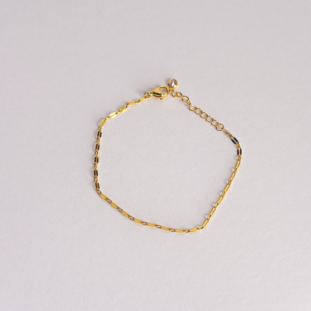 Gold bracelet on a light gray background