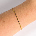Gold chain bracelet on a wrist with a neutral background