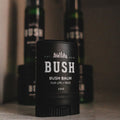Black container of Bush balm on a shelf with other similar products in the background.