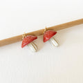 Pair of red and gold earrings on a white background