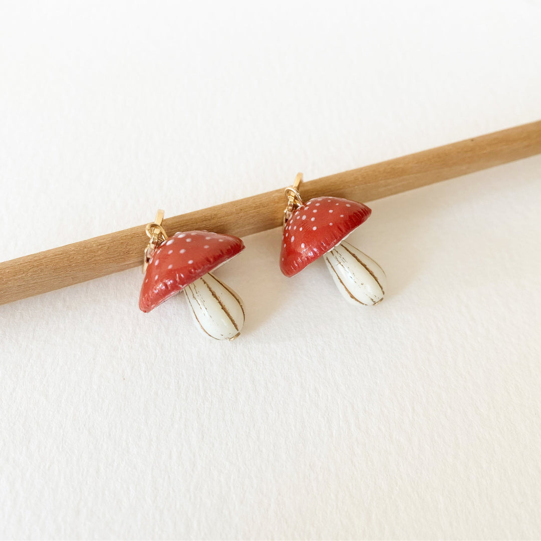 Pair of red and gold earrings on a white background