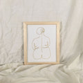 Framed abstract line art of a nude figure on a textured beige surface