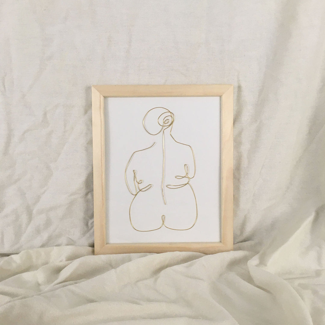 Framed abstract line art of a nude figure on a textured beige surface