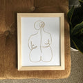 Framed abstract line art of a nude figure on a textured surface