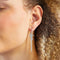 A set of silver earrings with interchangeable charms. The set includes two pairs of silver hoop earrings and three charms: a pearl, the word 