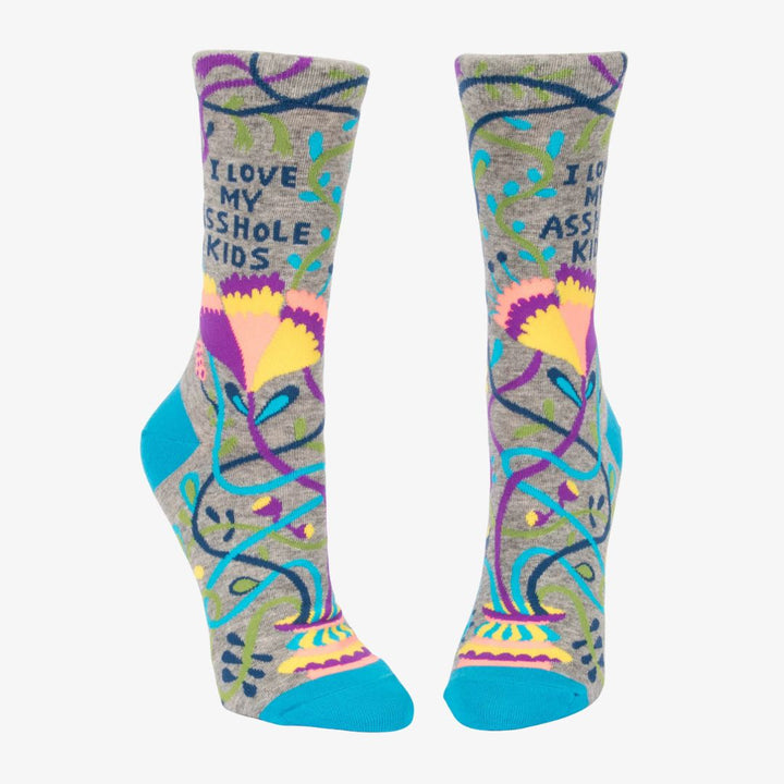 A pair of grey women's crew socks with vibrant, abstract floral and swirling line patterns in purple, yellow, pink, green, and blue. Text on one sock reads 