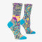 A pair of grey women's crew socks with vibrant, abstract floral and swirling line patterns in purple, yellow, pink, green, and blue. Text on one sock reads 
