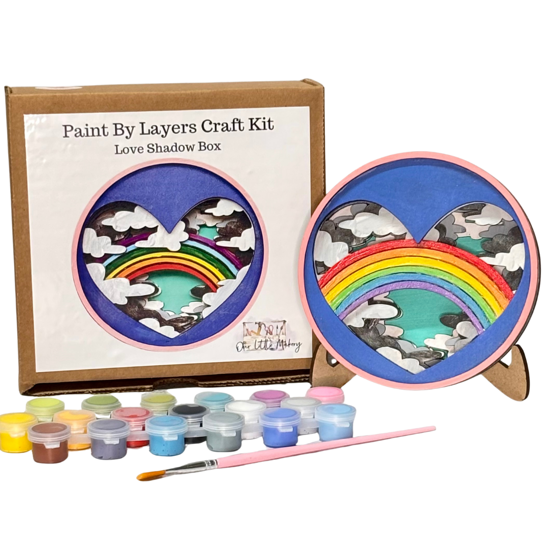 Paint by layers craft kit with rainbow design, paint bottles, and brush on a white background