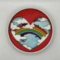 Decorative wall piece with a heart design featuring a rainbow and clouds on a gray background