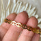 A gold-toned cuff bracelet with a pattern of repeating eye shapes.
