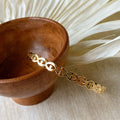 A gold-toned cuff bracelet with a pattern of repeating eye shapes.