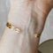 A gold-toned cuff bracelet with a pattern of repeating eye shapes.
