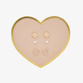 Heart-shaped jewelry tray with gold and pearl earrings on a white background