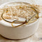 A gold-toned bangle bracelet with a bow design.