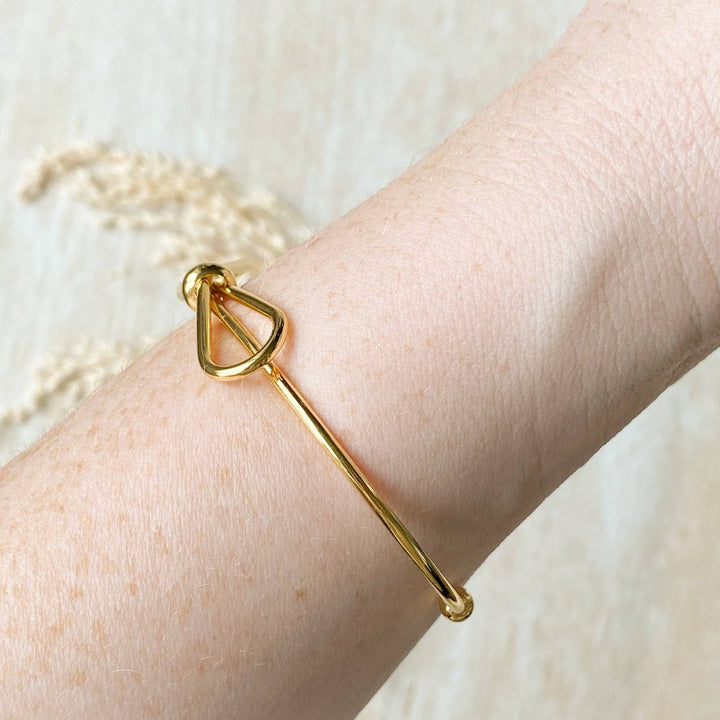 A gold-toned bangle bracelet with a bow design.