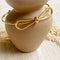 A gold-toned bangle bracelet with a bow design.