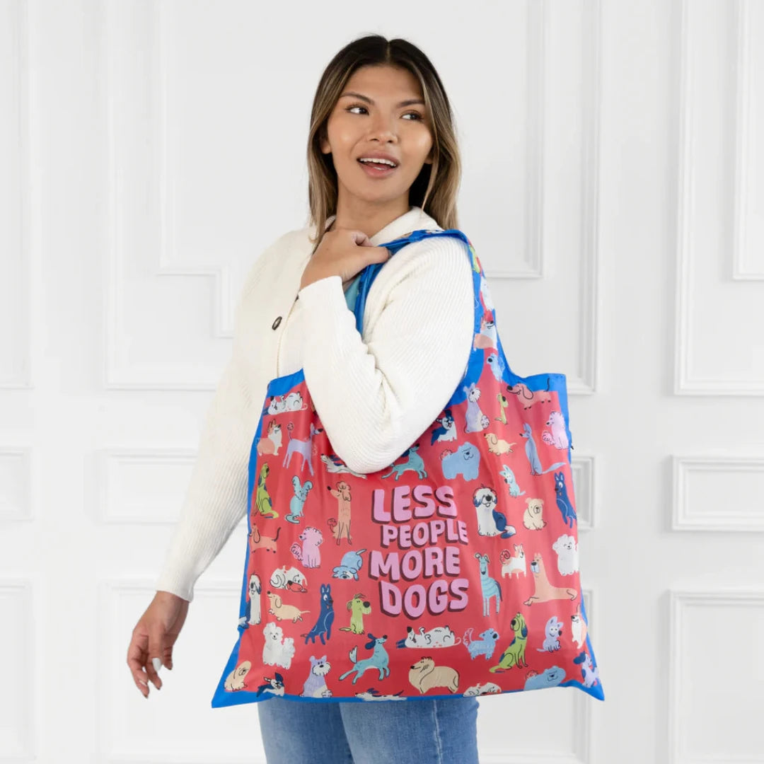 A colorful tote bag with a dog-themed design. The bag is covered in illustrations of various dog breeds in different poses, with the text "Less People More Dogs" printed in the center.