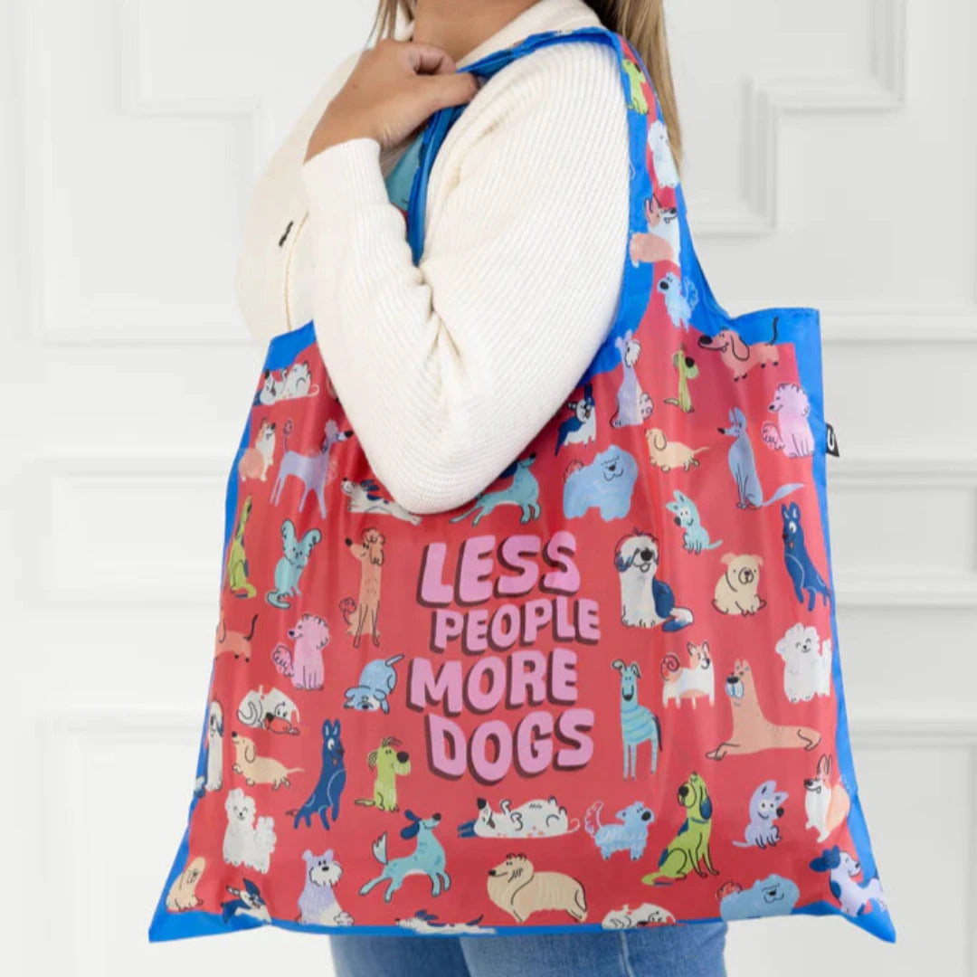 A colorful tote bag with a dog-themed design. The bag is covered in illustrations of various dog breeds in different poses, with the text "Less People More Dogs" printed in the center.