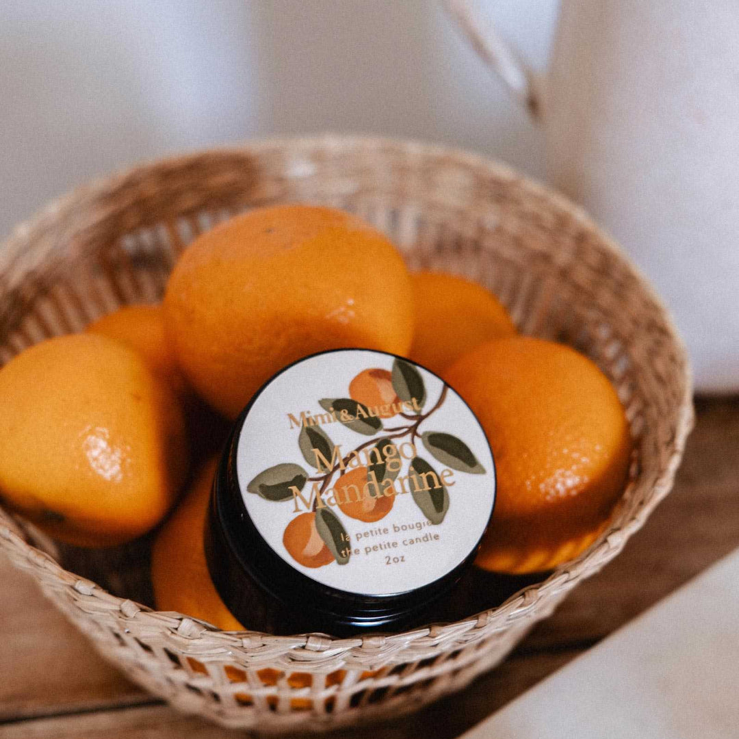 Jar of jam with a decorative label on top of mandarin oranges in a woven basket.
