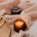 Candle and container on a soft pink fabric background