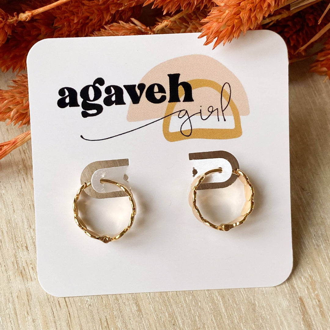 Gold hoop earrings on a 'agaveh girl' branded card with dried orange leaves in the background.