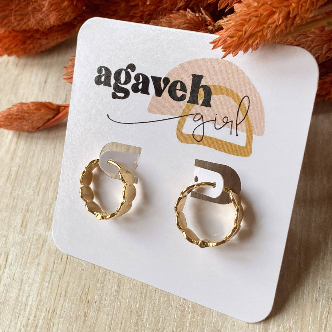 Gold hoop earrings on a 'agaveh girl' branded card with dried orange flowers in the background.
