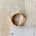 Gold ring on a wooden surface with a ruler for scale