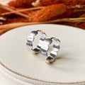 Silver hoop earrings on a white surface with dried plants in the background