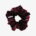 Maroon velvet scrunchie with a brand label on a white background