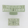 Two green metal hair clip stands on a white background