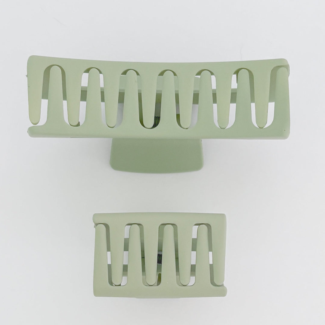 Two green metal hair clip stands on a white background