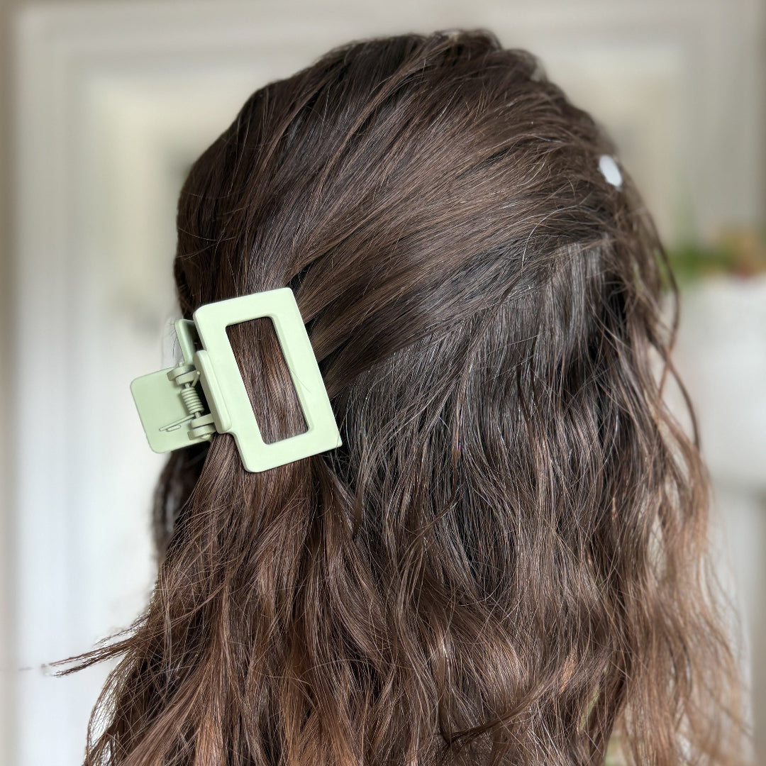 Close-up of wavy hair with a green hair clip against a blurred background