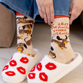 Person wearing socks with dog designs and red lip prints on white slippers.