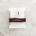Two burgundy hair ties on a white Barbays branded card against a marble background