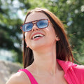 Woman wearing sunglasses and a pink top with a blurred green background