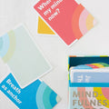 Mindfulness cards spread on a light textured surface with the card deck box visible at the lower right. Visible card text includes 'Where is my mind now?' and 'Breathe as anchor.