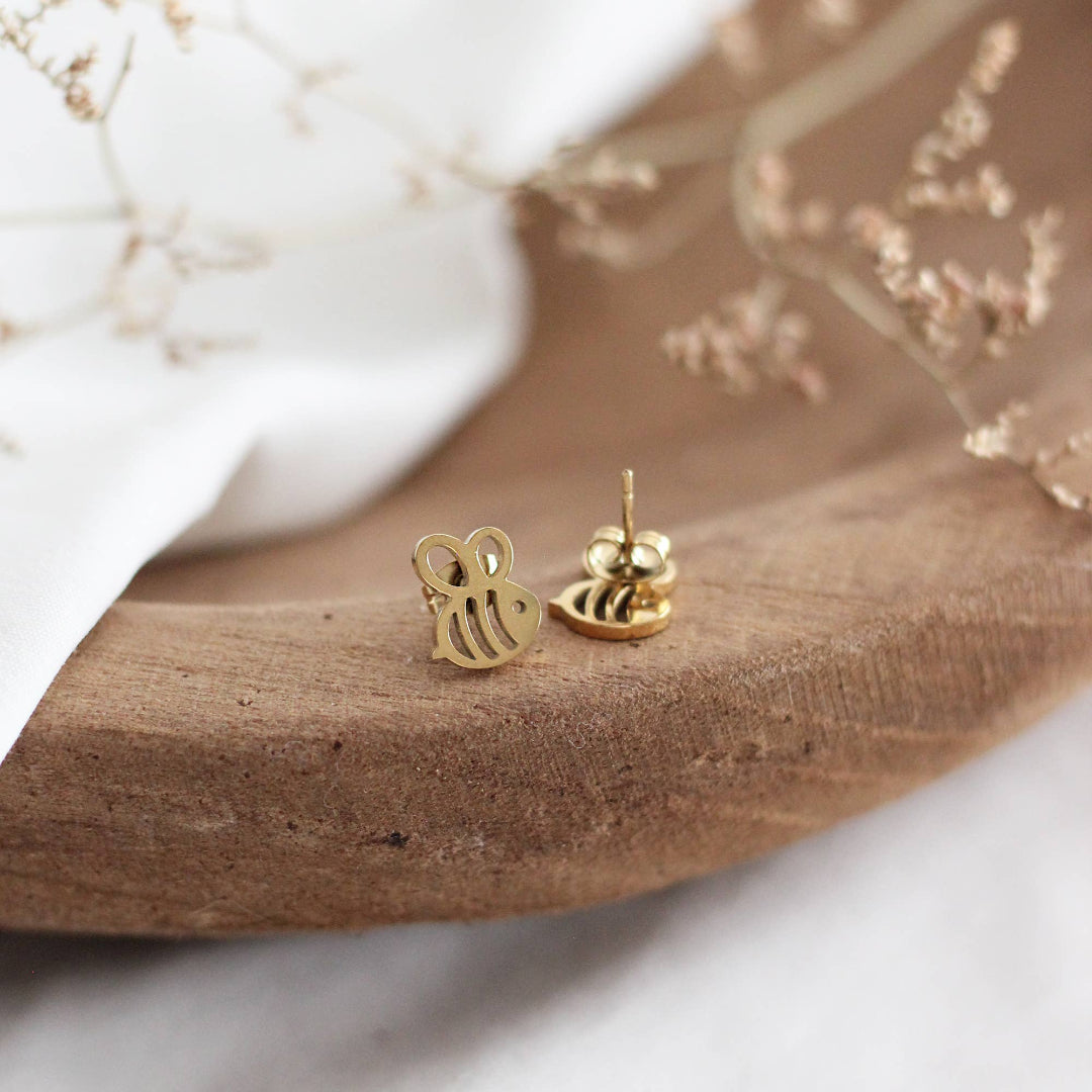 Gold earrings on a wooden surface with a white background