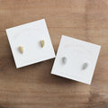 Two pairs of earrings on Birch Jewellery cards on a wooden surface