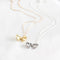 Two heart-shaped locket necklaces on a white card. One necklace has a gold-colored locket, and the other has a silver-colored locket. Both lockets have detailed designs and are attached to delicate chains.