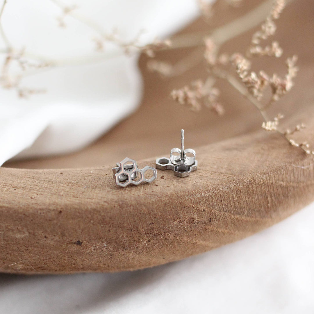Silver honeycomb design earrings on a wooden surface with a white background