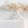 Silver honeycomb earrings on a white surface with dried grasses in the background