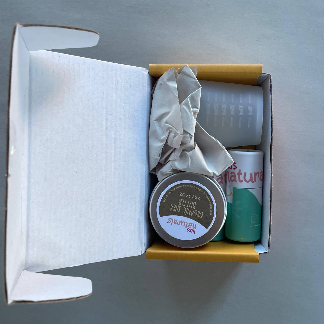 Open box containing a small jar and a can on a gray background