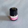 Small bottle of pink grapefruit essential oil with a black cap on a gray surface