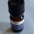 Small bottle of organic safflower oil with a black cap on a light gray background